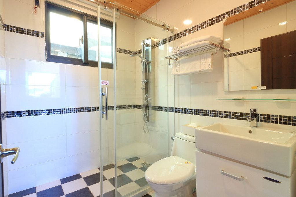 A bathroom with a glass-enclosed shower, a white toilet, and a sink with a mirror above it.