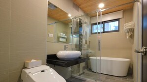 Ein modernes Badezimmer mit einer Glaskabine zur Dusche, einer freistehenden Badewanne und einer Toilette.