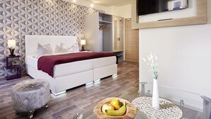 Ein modernes Schlafzimmer mit einem gemusterten Wand, einem Bett mit roter Decke, einem Kleiderschrank, einem Fernseher und einer Obstschale auf dem Boden.