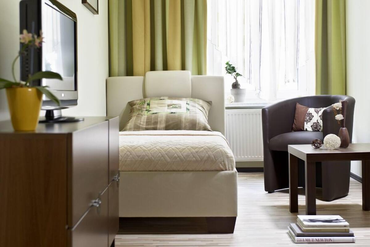 Une chambre à coucher avec un lit, une chaise, une table, un téléviseur et un radiateur.