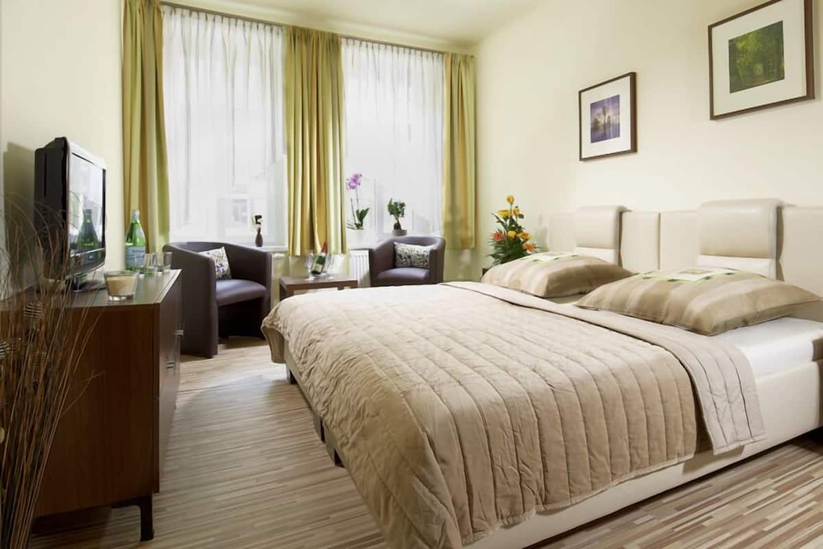 Une chambre d’hôtel avec un lit, un bureau, une chaise, une télévision et une fenêtre avec des rideaux.