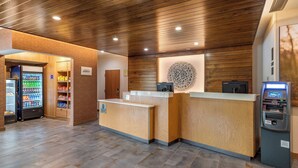 A reception area with a wooden reception desk, a vending machine, and a self-service kiosk. - Fairfield Inn & Suites by Marriott Helen (Helen)