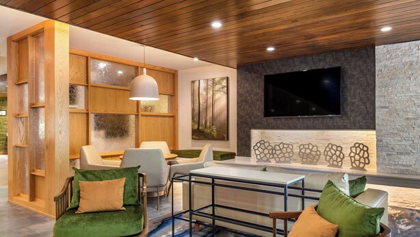 A modern lounge area with wooden shelving, comfortable seating, a flat-screen TV, and a stone accent wall. - Fairfield Inn & Suites by Marriott Helen (Helen)