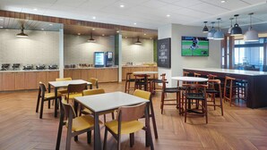 A modern restaurant with wooden flooring, yellow chairs, and a bar area. - Fairfield Inn & Suites by Marriott Helen (Helen)