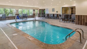A swimming pool with a slide, seating area, and a view of trees through large windows. - Fairfield Inn & Suites by Marriott Helen (Helen)