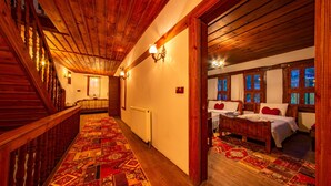 A wooden staircase with a patterned carpet leading to a bedroom with a bed and a window. - Beyzade Konak Otel (Safranbolu)
