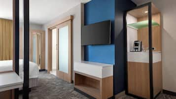 Une chambre d’hôtel équipée d’un lit, d’un téléviseur fixé au mur, d’une petite kitchenette et d’une armoire.