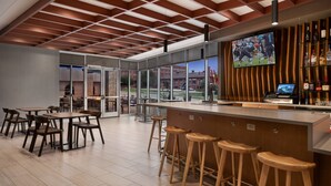 Un espace bar moderne avec des tabourets en bois, un comptoir et un écran de télévision.