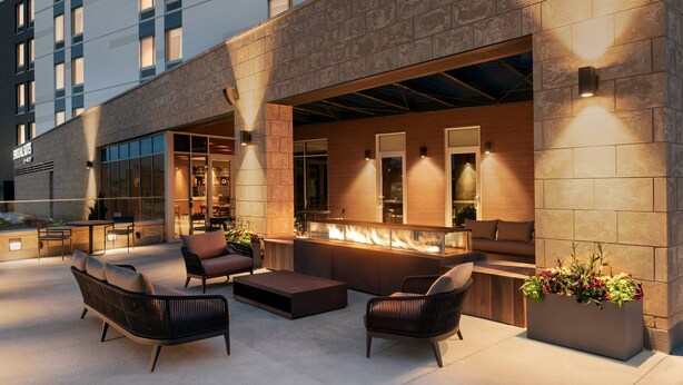 Un espace extérieur aménagé avec des meubles modernes, un bar et un grand bac à fleurs.