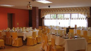 A banquet hall with multiple tables set for dining, yellow chairs, and a brick wall. - Hotel Rural Casa Migio (Mieres)