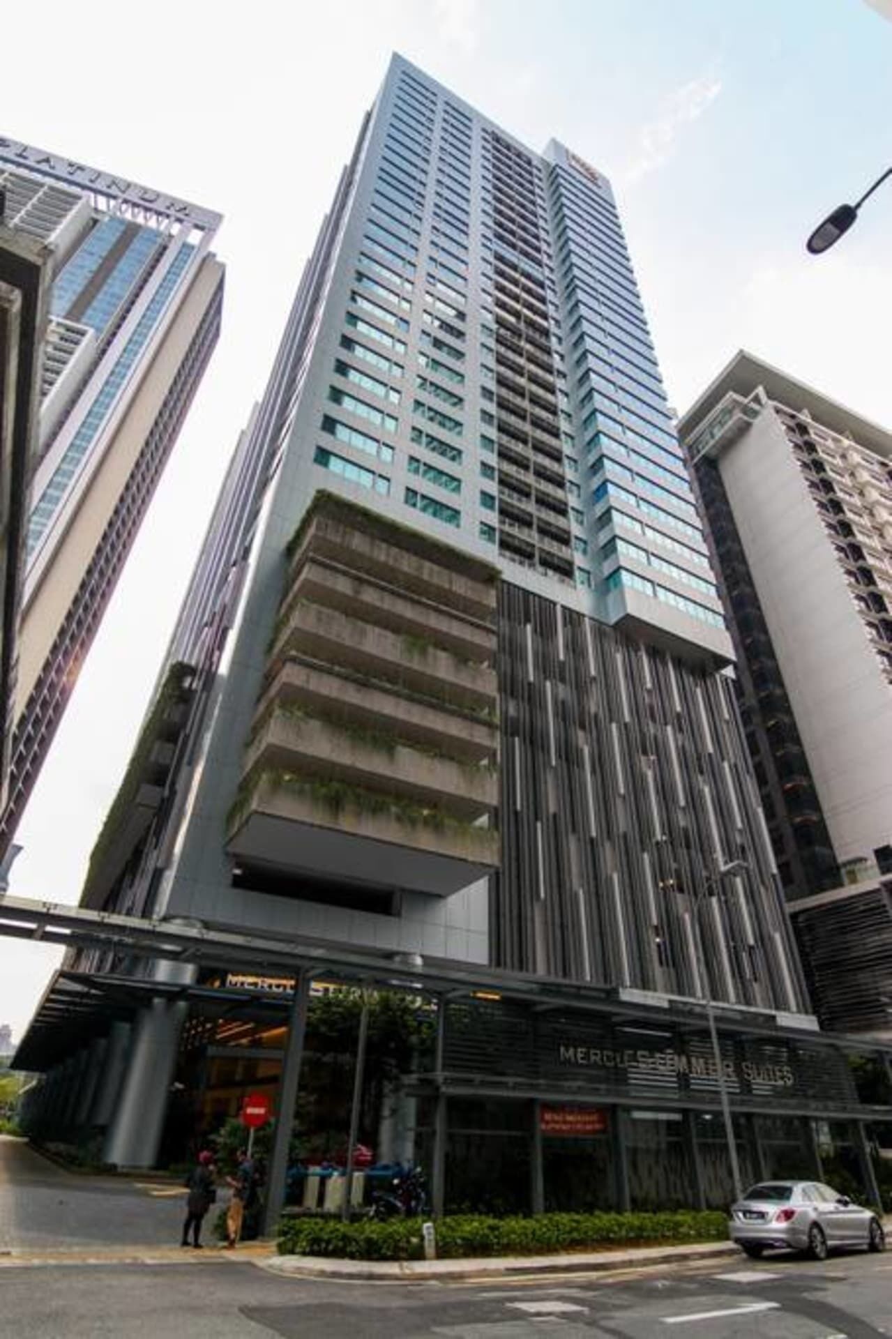 A modern high-rise building with a prominent corner entrance, large glass windows, and a visible storefront with signage.