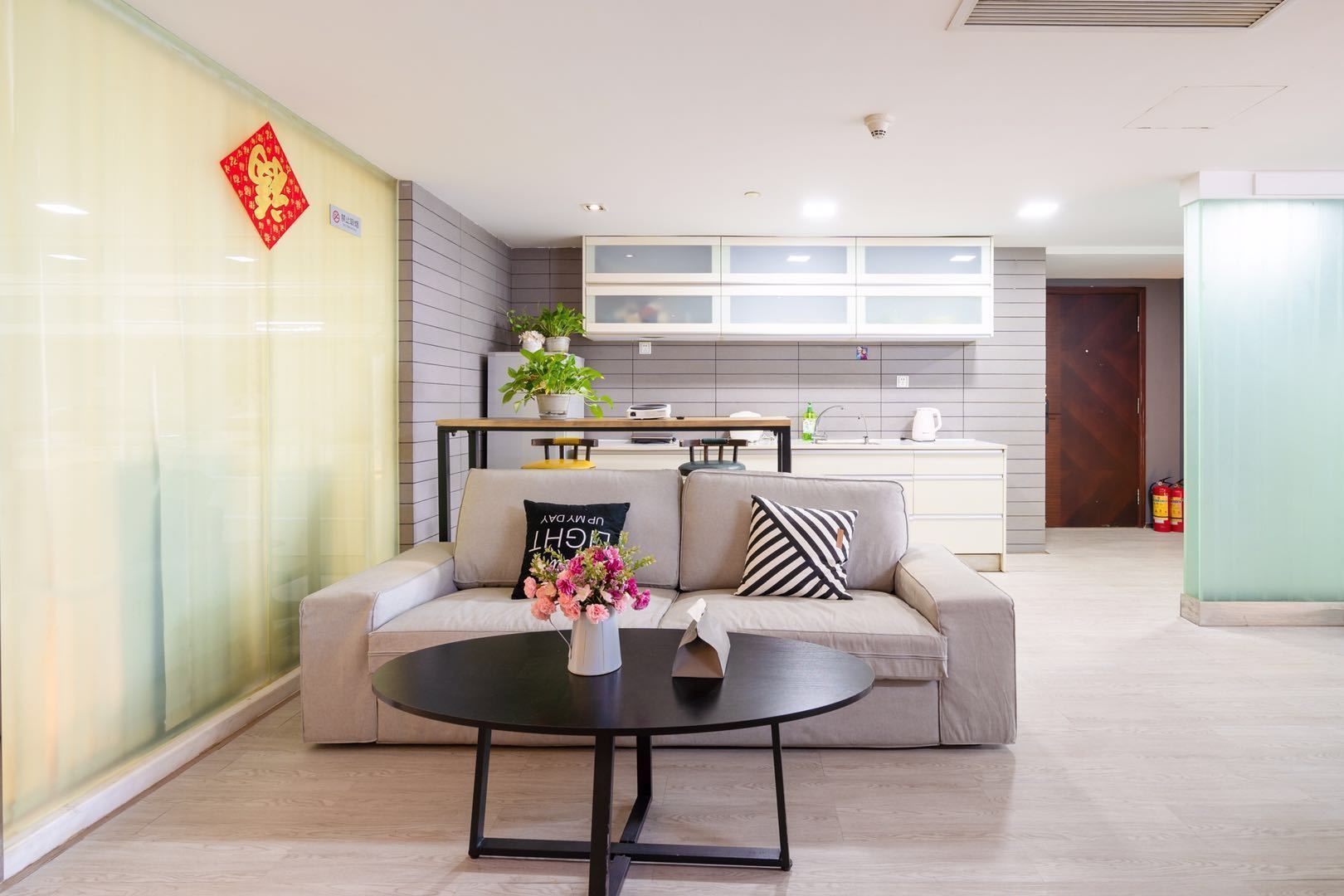 A modern living room with a sofa, coffee table, and a kitchen in the background.