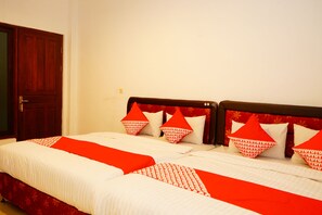 A hotel room with two beds, each with red and white bedding and matching pillows. - Hotel Meigah (Tanjung Pandan)