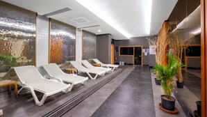 A modern indoor pool area with white lounge chairs, a tiled floor, and potted plants. - The Raga Side - Adults Only - All inclusive (Manavgat)