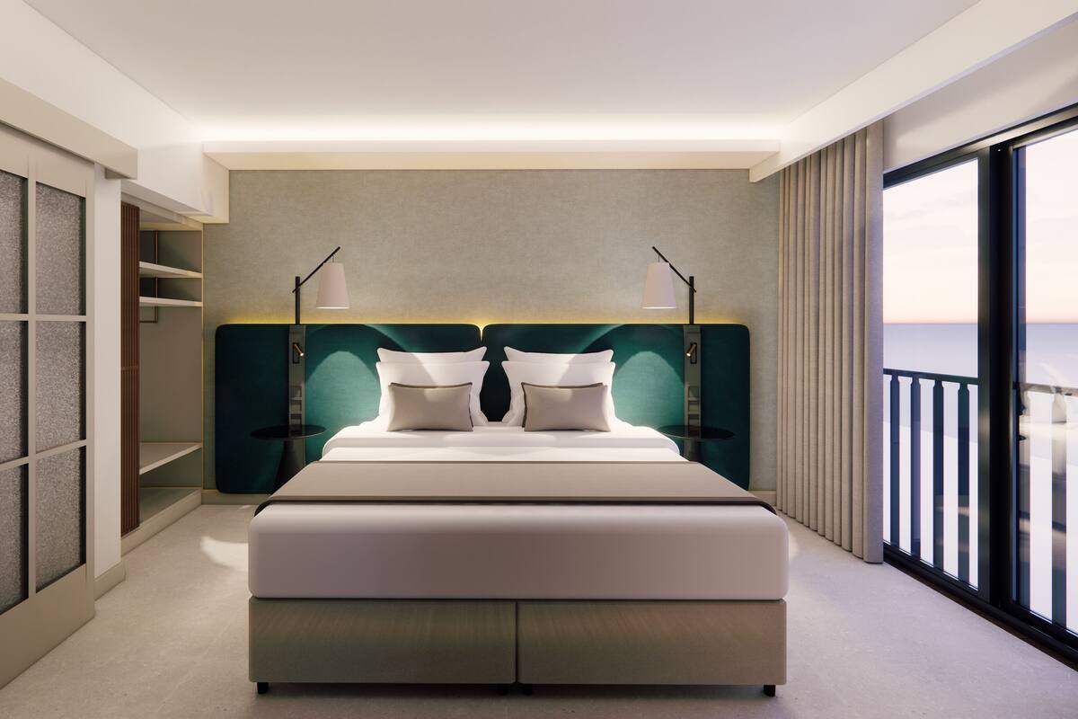 Una habitación de hotel moderna con una cama grande, un vestidor, vistas al mar y un balcón.