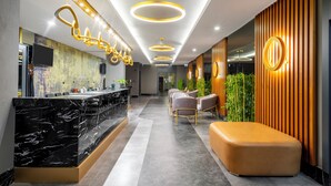 A modern hotel lobby with a marble reception desk, seating area, and a large wooden accent wall. - The Raga Side - Adults Only - All inclusive (Manavgat)