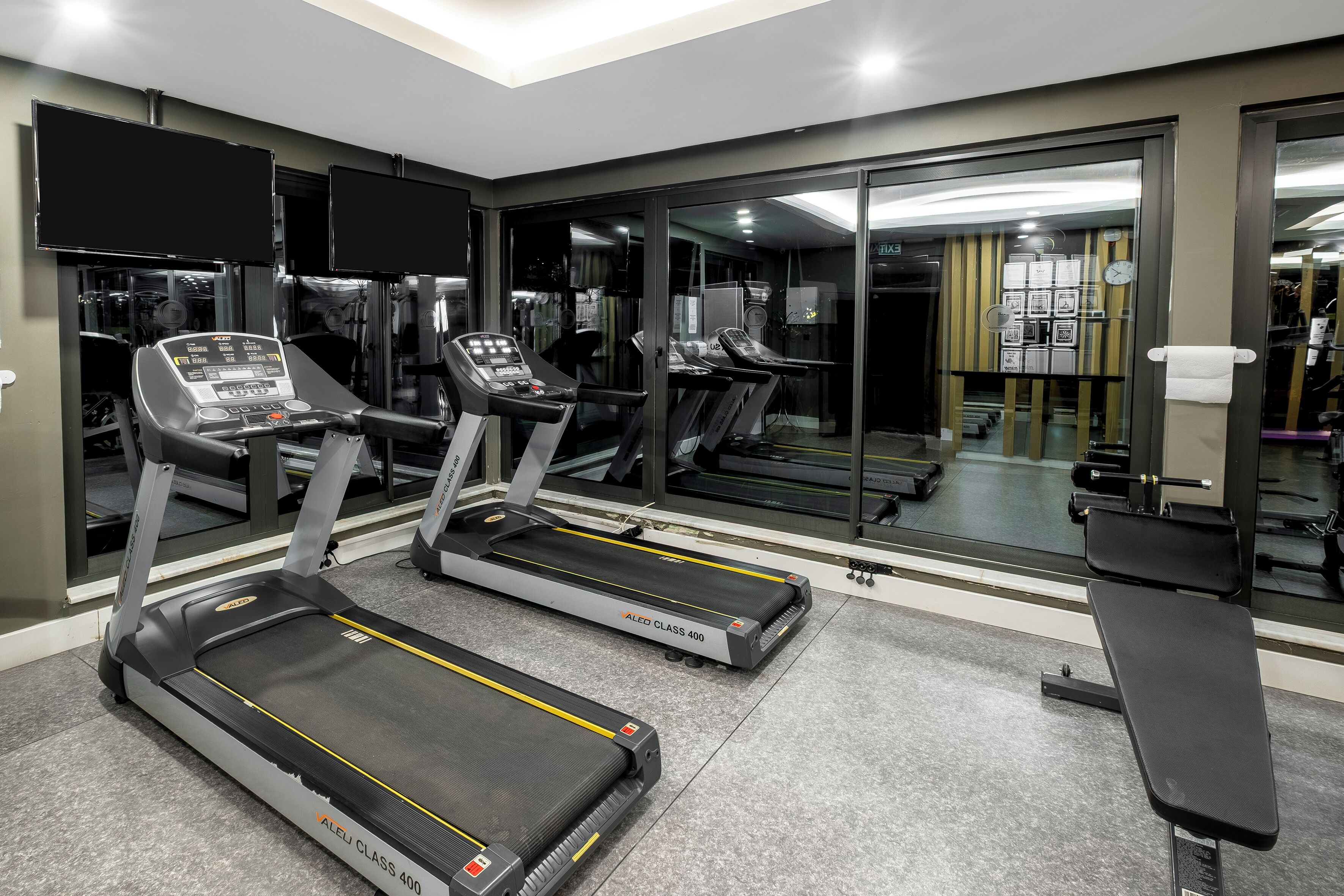 A gym with treadmills, weight machines, and a bench.
