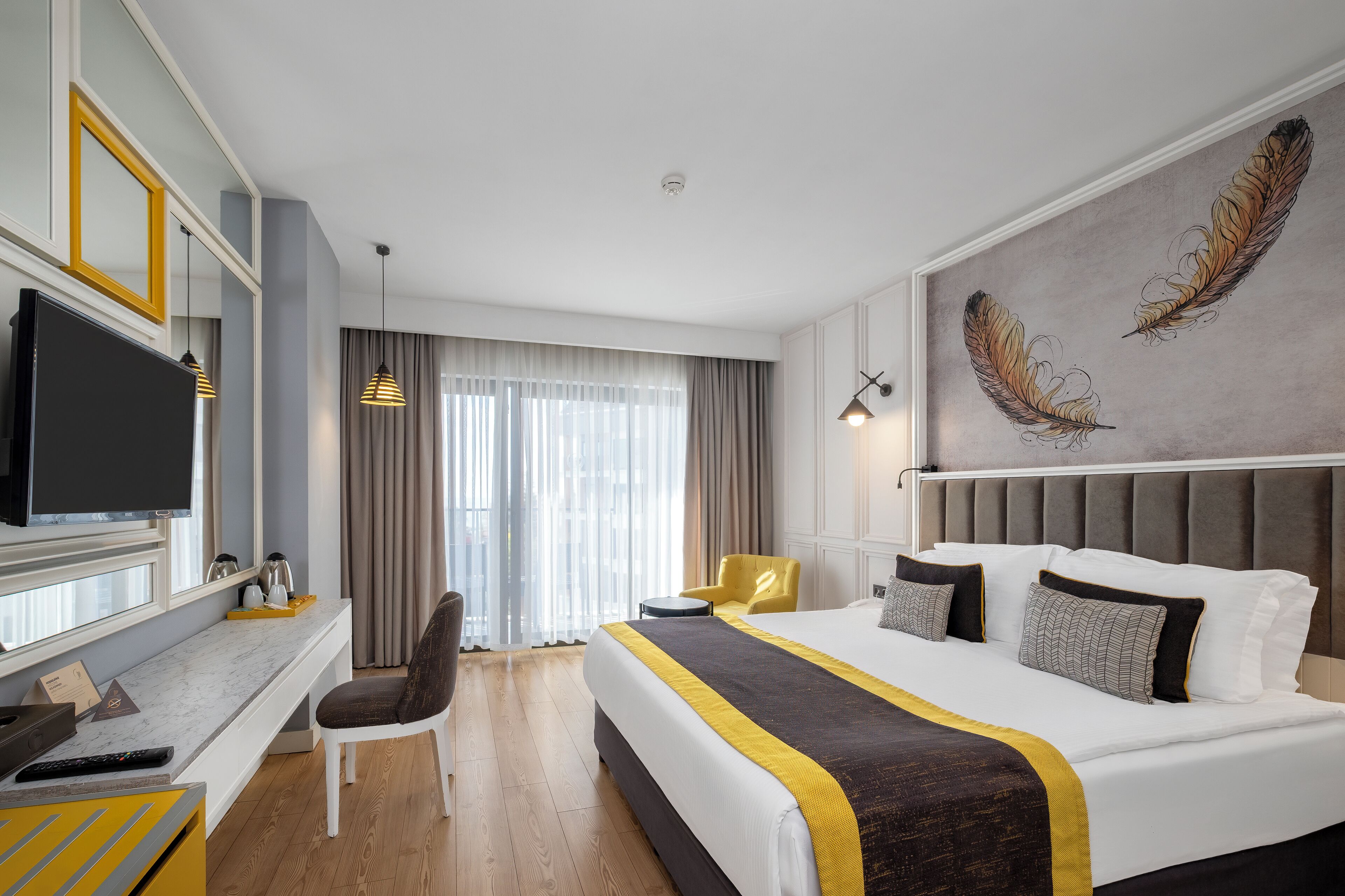 A hotel room with a large bed, a desk with a TV, a chair, and a large window with curtains.
