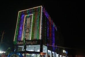 A hotel with a prominent vertical light display and a sign reading "Hotel Amjias."
