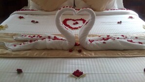 Een bed versierd met een hart van witte handdoeken en rozenblaadjes.