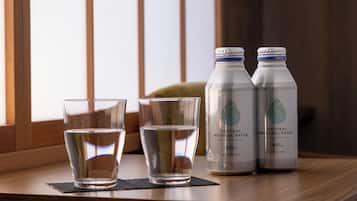Two bottles of natural mineral water and two glasses on a wooden table near a window.