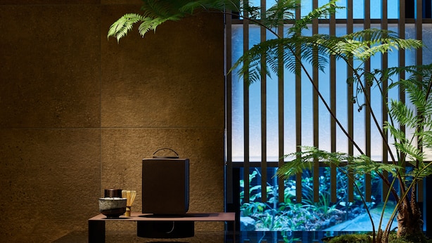A modern interior with a dark-toned reception desk, a small wooden cabinet, and a potted plant with green foliage. - Mitsui Garden Hotel Kyoto Station (Kyoto)
