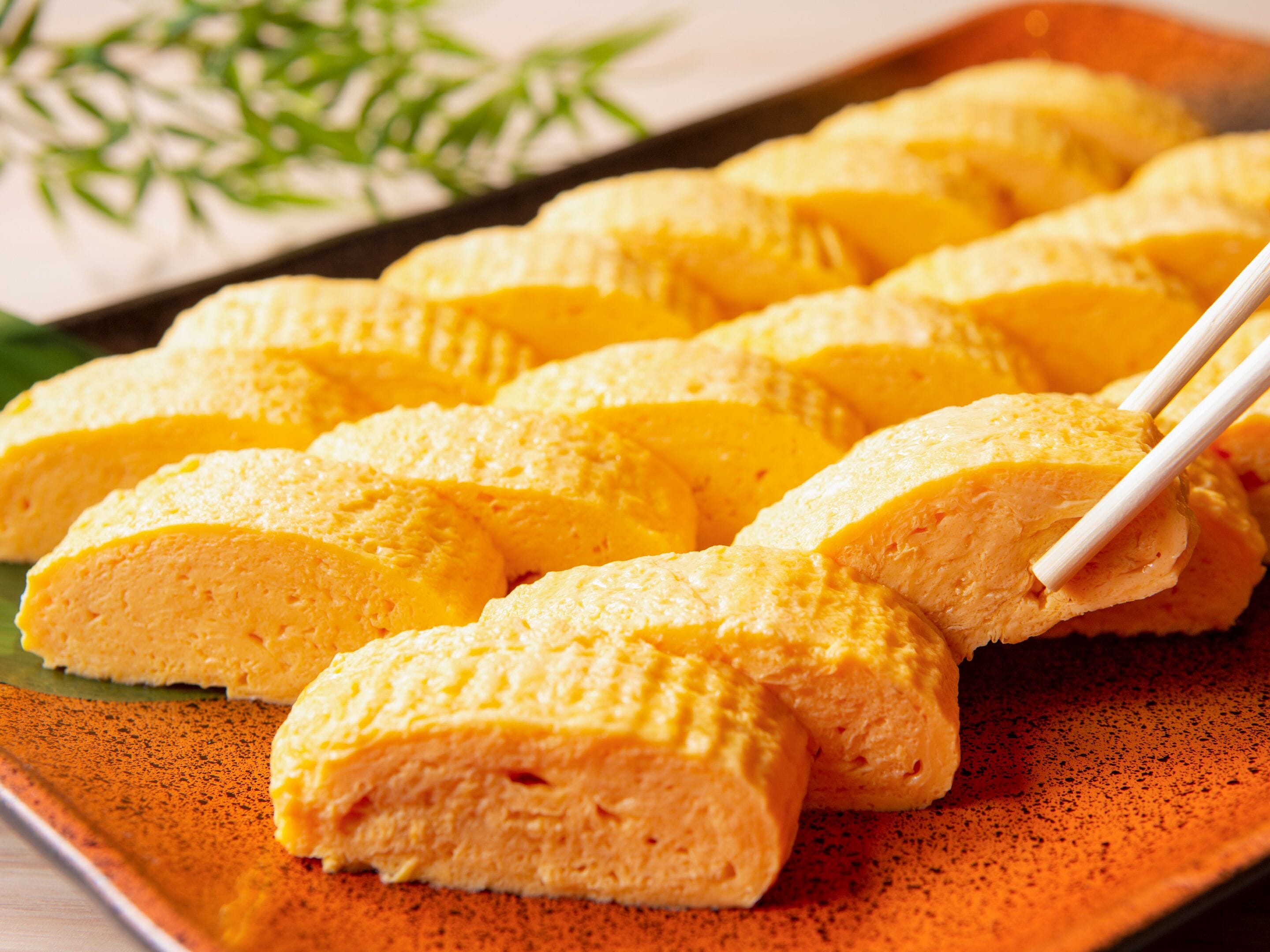 A tray of yellow food items, possibly a dessert, arranged on a plate with chopsticks.