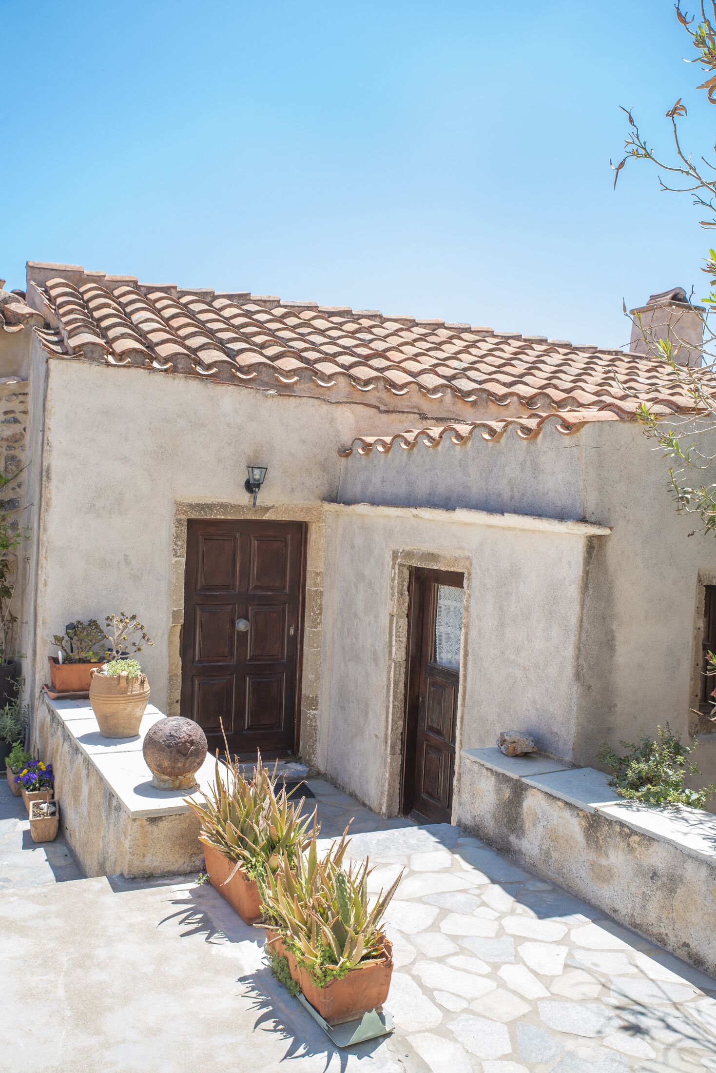 A building with a tiled roof, a wooden door, and potted plants.