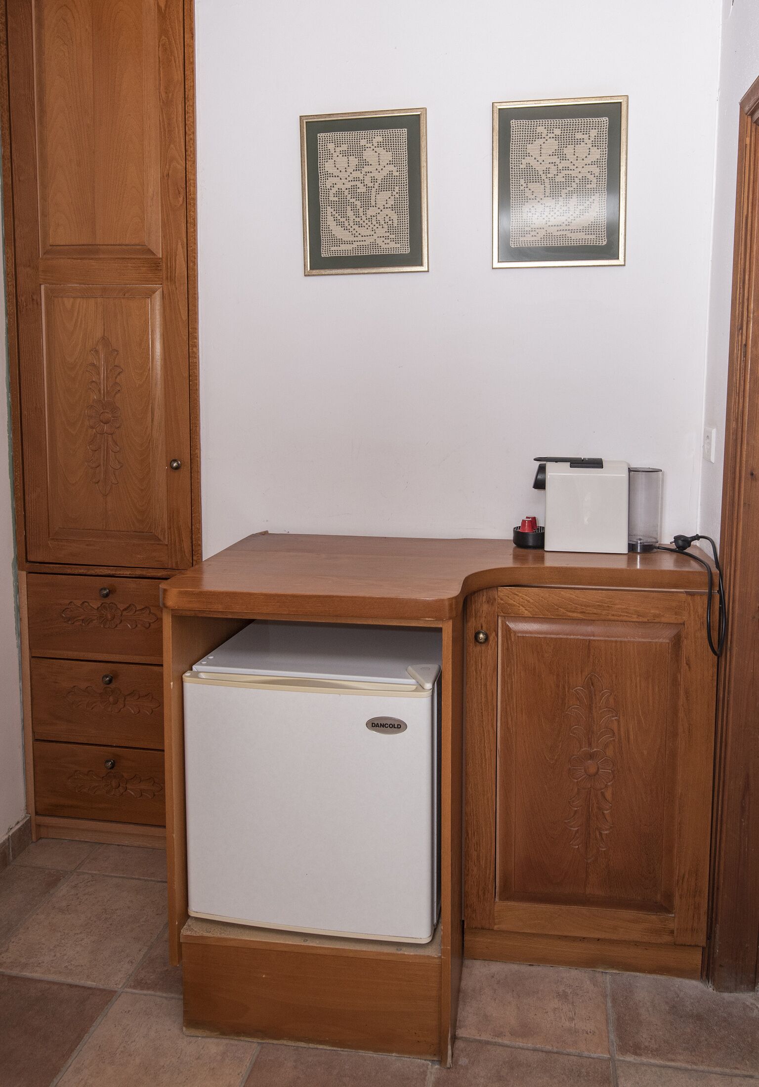 A compact kitchen with a built-in refrigerator, wooden cabinetry, and two framed wall decorations.