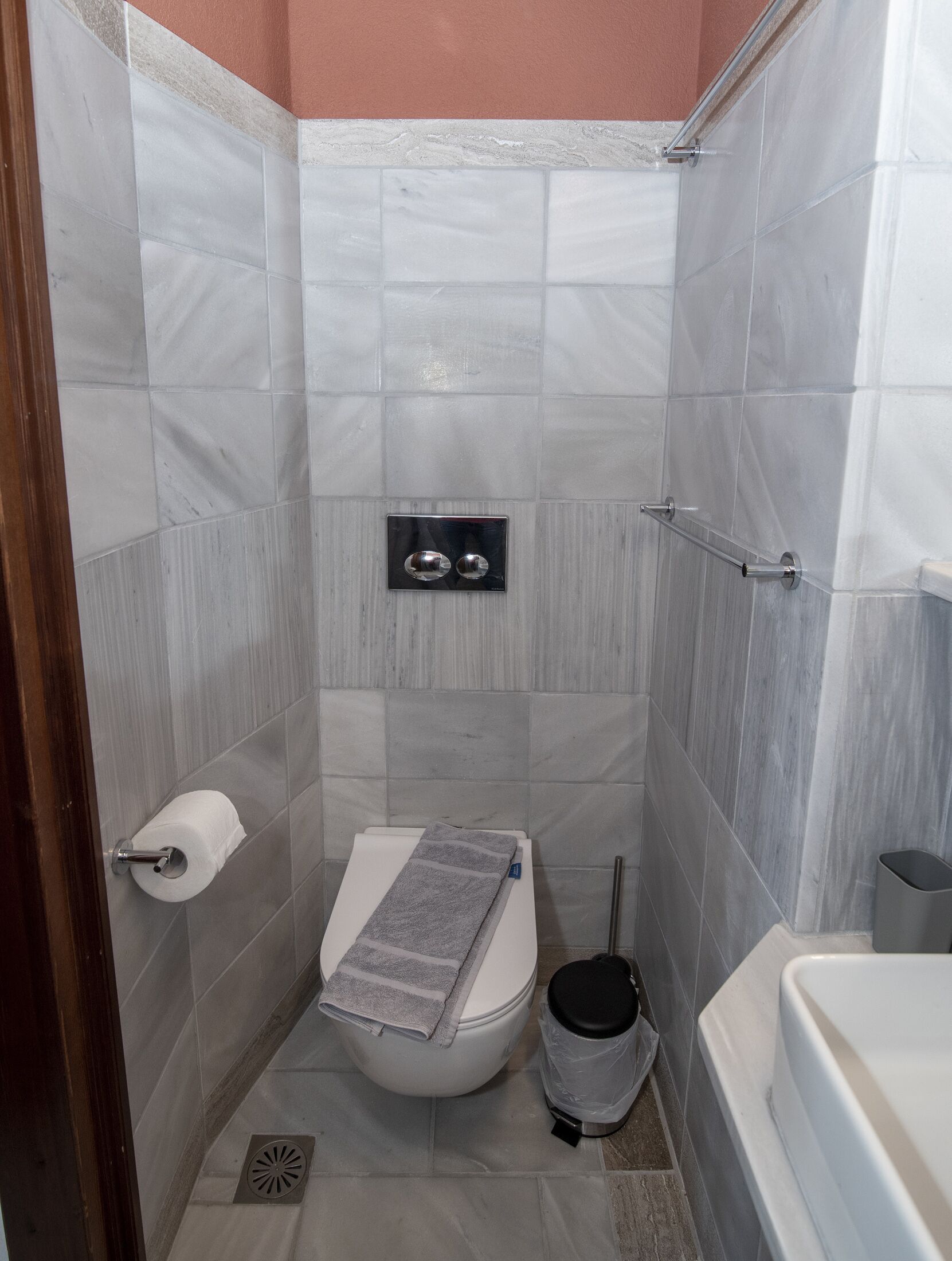 Un baño pequeño y moderno con inodoro, una toalla, un cesto de basura y una zona de ducha.