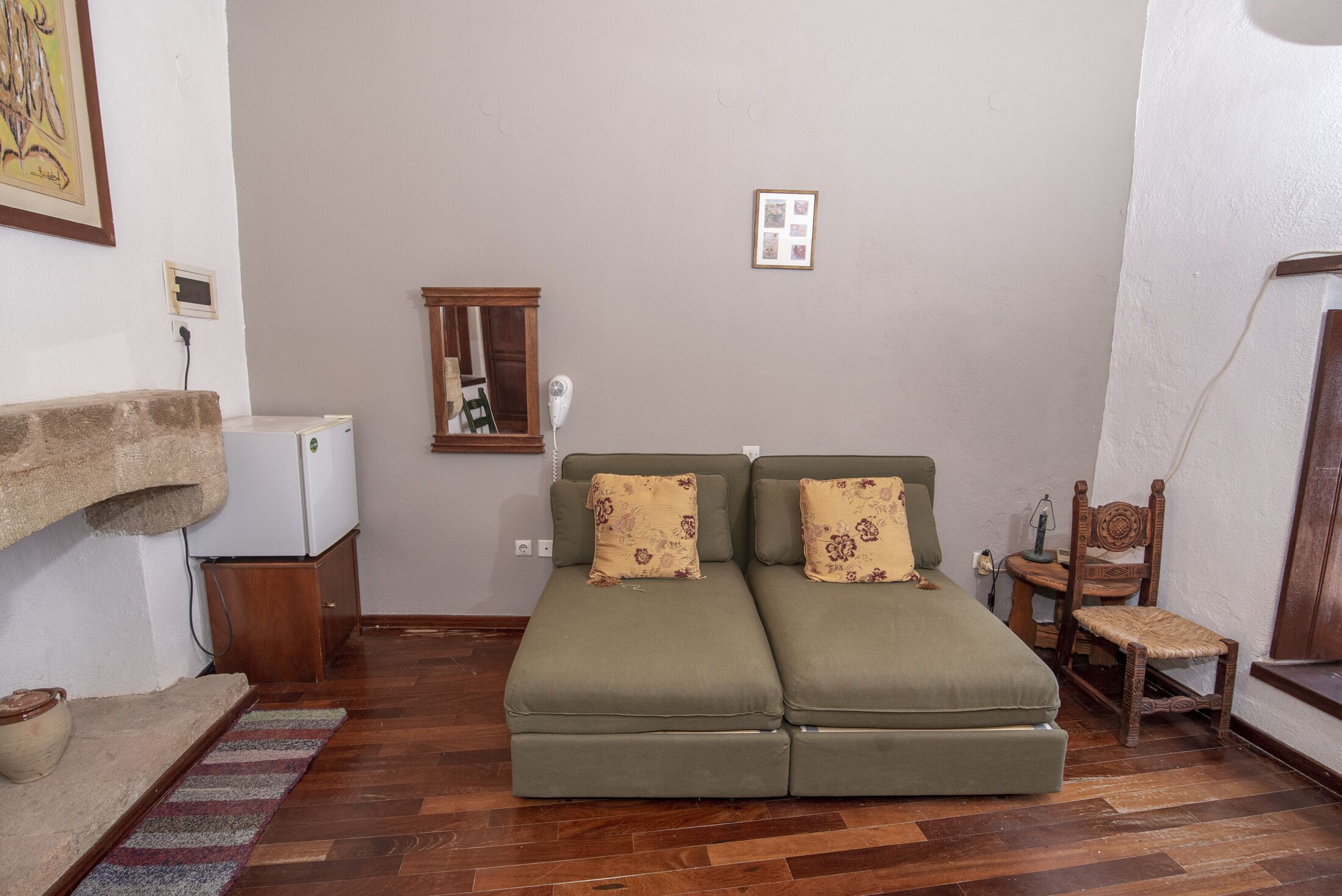 A cozy room with a green sofa, a wooden chair, a small table, and a white appliance.