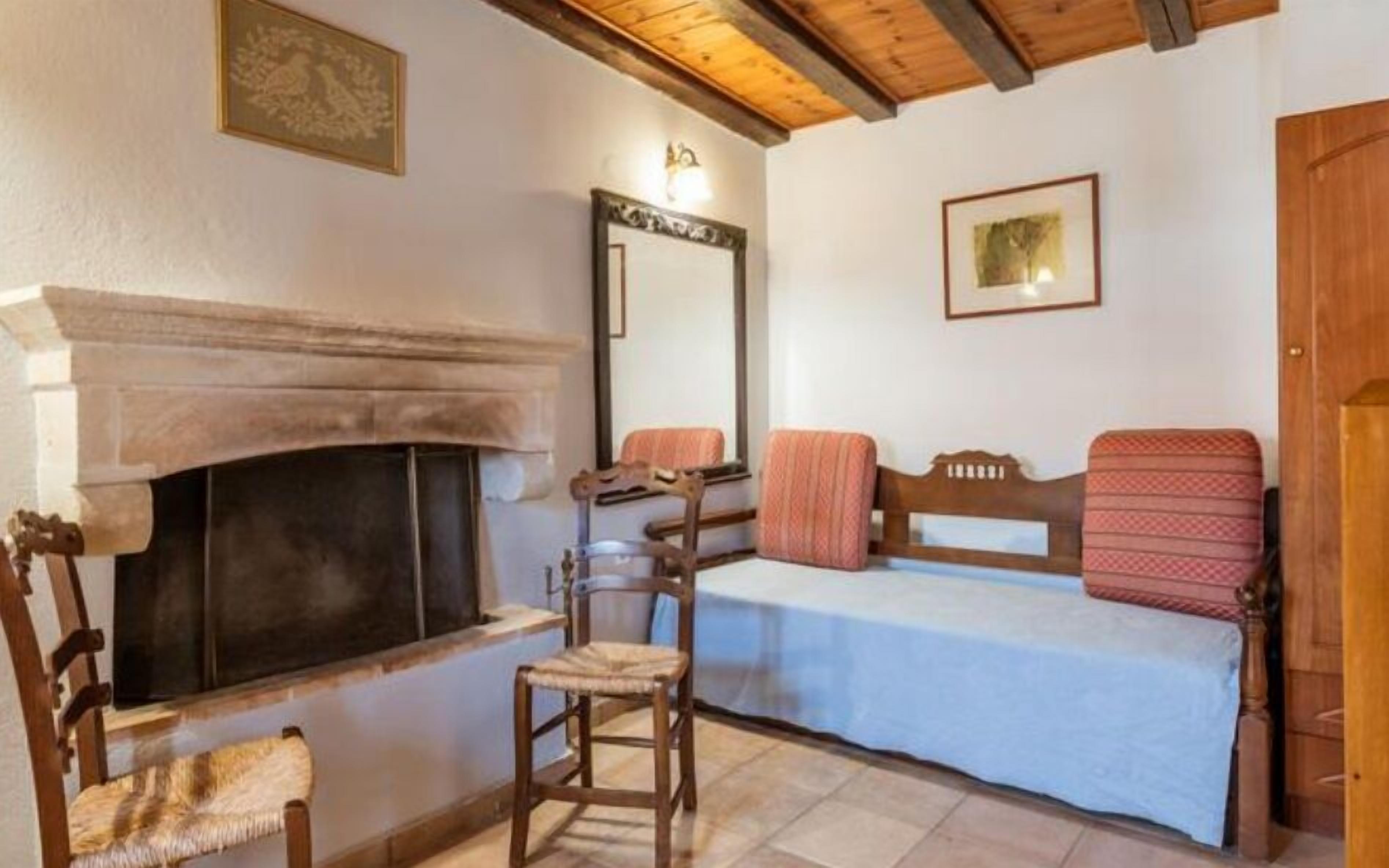 A cozy room with a fireplace, a bed with a headboard, a chair, and a mirror on the wall.