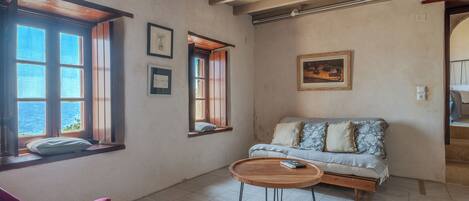 Una habitación con sofá, una mesita de madera y una ventana con vista al mar.