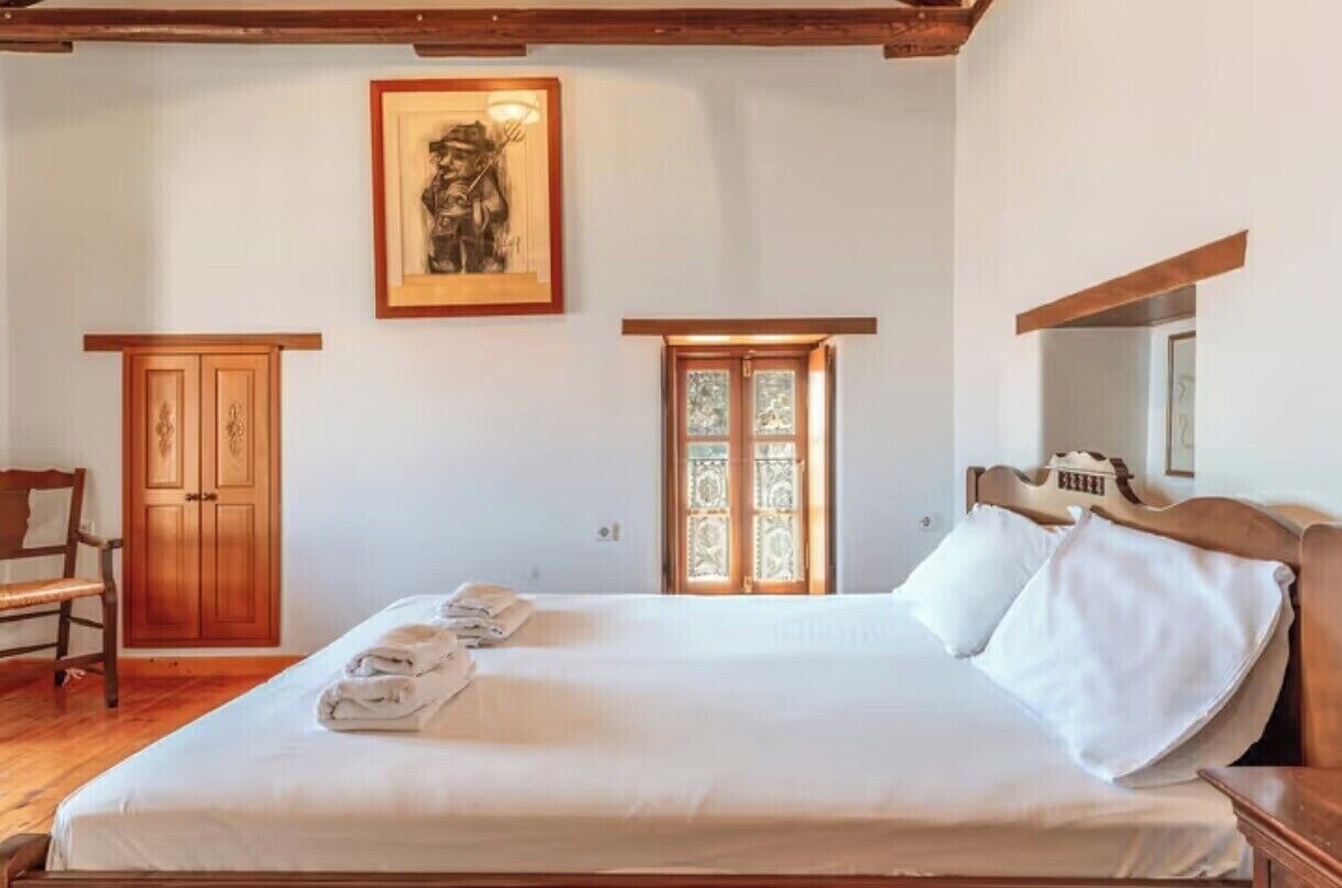 Un dormitorio con una cama grande, un armario de madera y una obra de arte enmarcada en la pared.