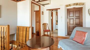 Una habitación acogedora con una mesa de comedor de madera, un sofá con un cojín estampado y una puerta de madera.