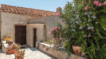 A building with a tiled roof and a small entrance. There are potted plants and flowers around the entrance.