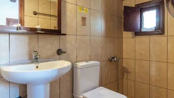 A bathroom with a white sink, toilet, and a window with a wooden frame.
