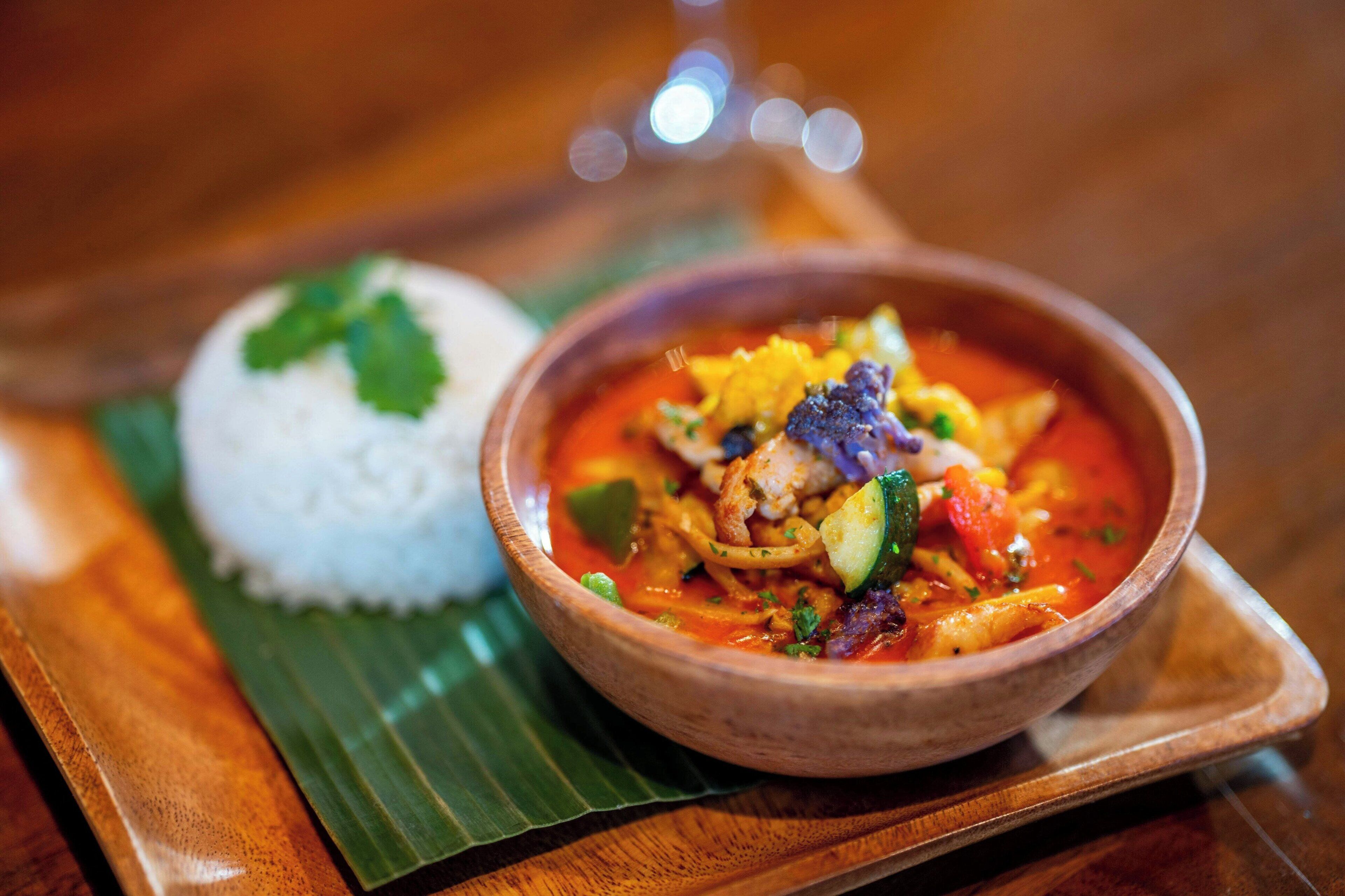 A bowl of soup with rice on a wooden tray.