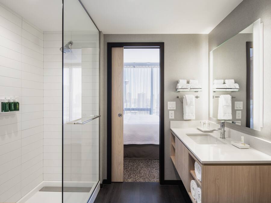 Un baño moderno con cabina de ducha de vidrio, un espejo grande y un mueble de tocador con lavabo.