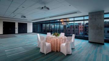 A conference room with a large table set for a meeting, large windows with a city view, and a carpeted floor.