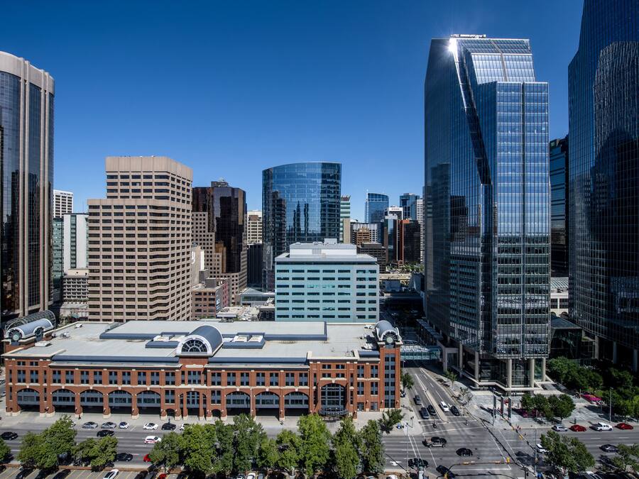 A cityscape with modern high-rise buildings, a prominent red-brick building with a dome, and a clear blue sky.
