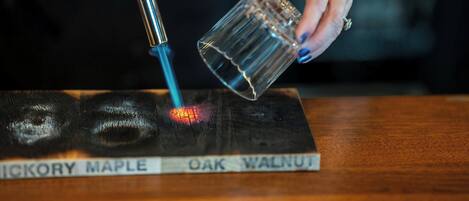 Una persona usando un soplete sobre una superficie de madera con letreros que dicen "OAK WALNUT".