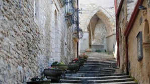 A narrow stone staircase in a historic building with arched doorways and flower pots at the bottom. - Hotel Miramonti (Gangi)