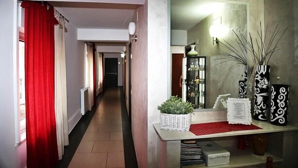 A hallway with a red curtain, a mirror, and decorative vases on a console table. - Hotel Miramonti (Gangi)