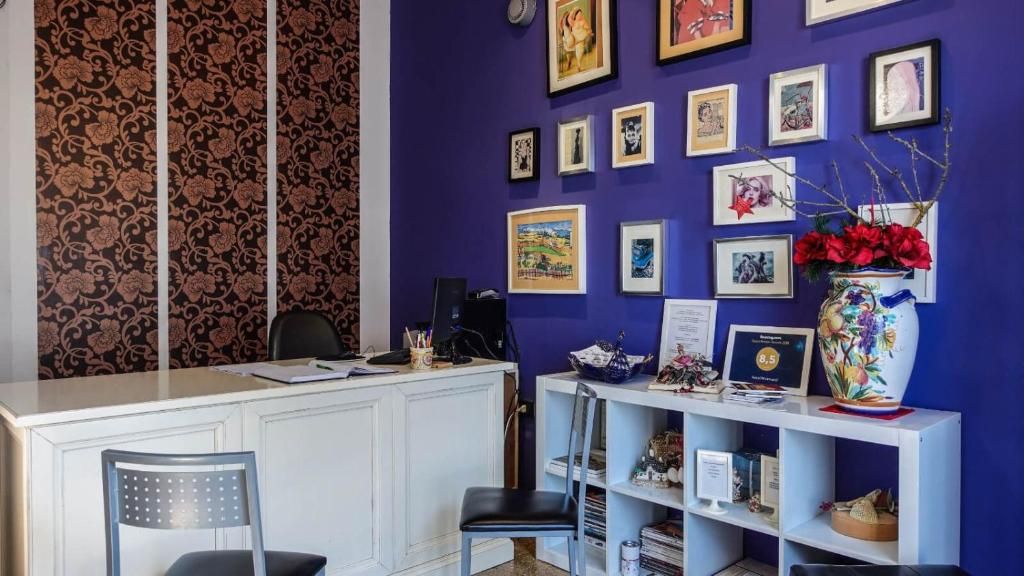 Un'area reception con scrivania, sedie e una parete decorata con opere d'arte incorniciate.
