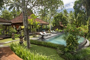 A pool area with lounge chairs, a small garden, and a gazebo.