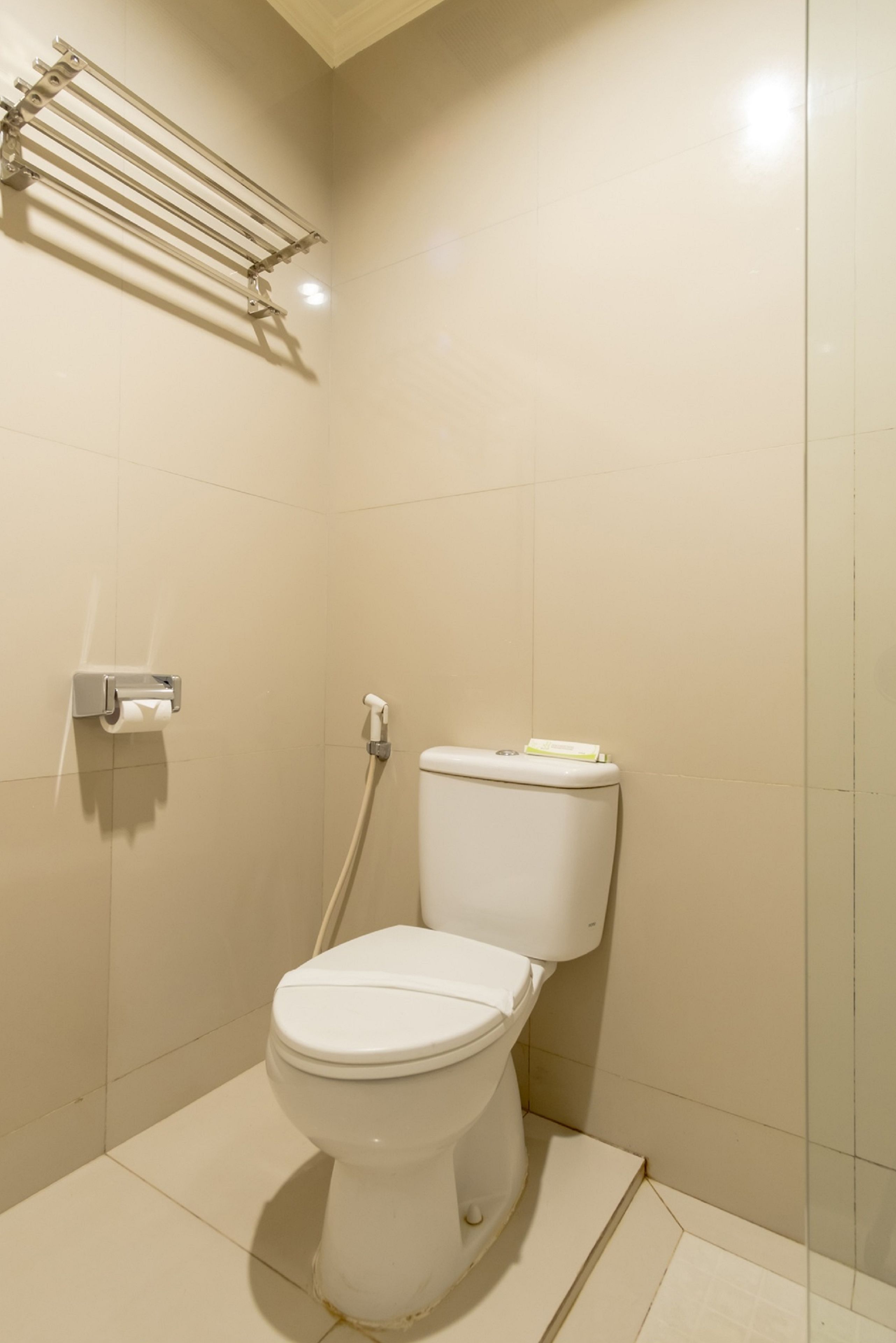Casa de banho pequena e limpa, com sanita, secador de mãos e dispensador de papel.