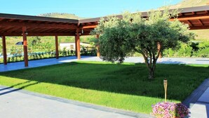 Ein überdachter Außenbereich mit gepflegtem Rasen, einem Blumentopf und einer Pergola.