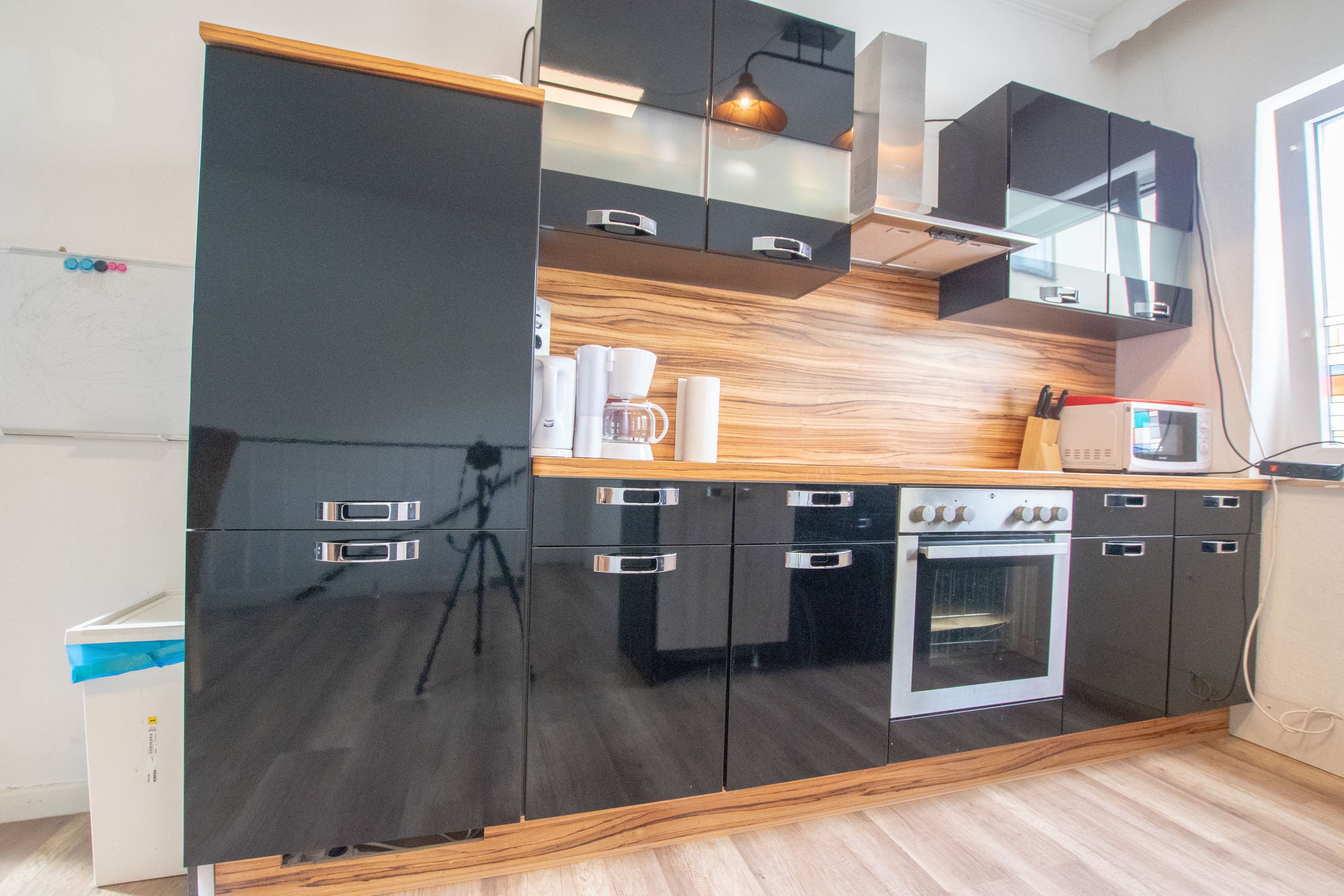 A modern kitchen with black cabinets, a wooden countertop, and a built-in oven.
