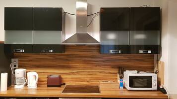 A kitchen with dark cabinets, a wooden countertop, a coffee maker, a toaster, and a microwave.